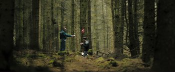 Movie still from “The Disappearance of Alice Creed” (2009), directed by J Blakeson – Two men in the woods playing frisbee golf; Extreme Wide shot, Over the shoulder angle