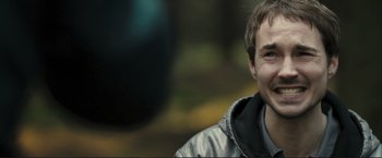 Movie still from “The Disappearance of Alice Creed” (2009), directed by J Blakeson – A young man smiles while wearing a jacket; Close Up shot, Over the shoulder angle