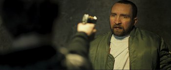 Movie still from “The Disappearance of Alice Creed” (2009), directed by J Blakeson – A man holding a gun in front of another man; Close Up shot, Over the shoulder angle