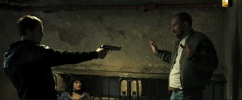 Movie still from “The Disappearance of Alice Creed” (2009), directed by J Blakeson – A man is holding a gun up to a woman's face; Medium shot, Over the shoulder angle
