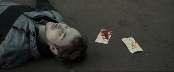 Movie still from “The Disappearance of Alice Creed” (2009), directed by J Blakeson – A man laying on the ground next to a piece of paper; Close Up shot, Overhead angle