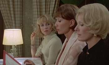 Movie still from “The Discreet Charm of the Bourgeoisie” (1972), directed by Luis Buñuel – A group of women sitting next to each other in a room; Medium shot, Over the shoulder angle