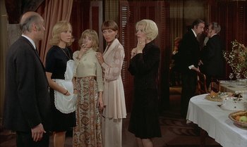 Movie still from “The Discreet Charm of the Bourgeoisie” (1972), directed by Luis Buñuel – A group of women standing next to each other in a room; Medium shot, High angle
