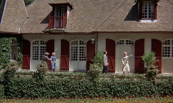 Movie still from “The Discreet Charm of the Bourgeoisie” (1972), directed by Luis Buñuel – A group of people standing on the side of a house; Extreme Wide shot, Low angle