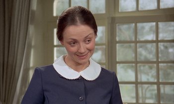 Movie still from “The Discreet Charm of the Bourgeoisie” (1972), directed by Luis Buñuel – A woman in a blue dress and a white collar smiling; Close Up shot, High angle