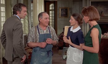 Movie still from “The Discreet Charm of the Bourgeoisie” (1972), directed by Luis Buñuel – A group of people standing in a living room talking; Medium shot, Over the shoulder angle