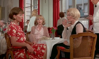 Movie still from “The Discreet Charm of the Bourgeoisie” (1972), directed by Luis Buñuel – A group of women sitting at a table in a restaurant; Medium shot, Over the shoulder angle