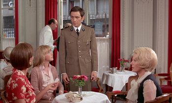 Movie still from “The Discreet Charm of the Bourgeoisie” (1972), directed by Luis Buñuel – A man in a uniform standing in front of two women; Medium shot, Over the shoulder angle