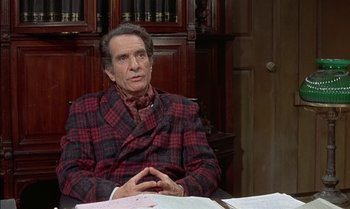 Movie still from “The Discreet Charm of the Bourgeoisie” (1972), directed by Luis Buñuel – An older man wearing a red and black plaid suit; Medium shot, High angle