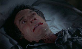 Movie still from “The Discreet Charm of the Bourgeoisie” (1972), directed by Luis Buñuel – A man with blood on his face laying in a bed; Close Up shot, High angle