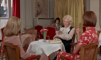 Movie still from “The Discreet Charm of the Bourgeoisie” (1972), directed by Luis Buñuel – A group of people sitting around a table; Medium shot, Over the shoulder angle