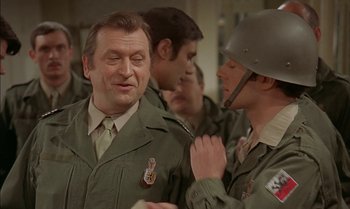 Movie still from “The Discreet Charm of the Bourgeoisie” (1972), directed by Luis Buñuel – A group of men standing next to each other in uniforms; Close Up shot, Over the shoulder angle
