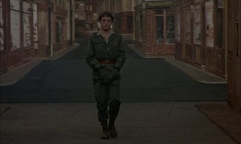 Movie still from “The Discreet Charm of the Bourgeoisie” (1972), directed by Luis Buñuel – A man in a military uniform walking down a street; Wide shot, Low angle