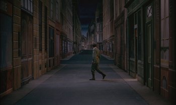 Movie still from “The Discreet Charm of the Bourgeoisie” (1972), directed by Luis Buñuel – A man walking down a street at night; Wide shot, High angle