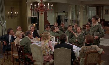 Movie still from “The Discreet Charm of the Bourgeoisie” (1972), directed by Luis Buñuel – A group of people sitting around a table eating food; Wide shot, High angle