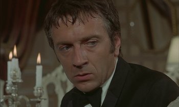 Movie still from “The Discreet Charm of the Bourgeoisie” (1972), directed by Luis Buñuel – A person wearing a suit and tie; Close Up shot, Low angle