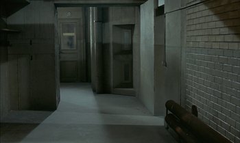 Movie still from “The Discreet Charm of the Bourgeoisie” (1972), directed by Luis Buñuel – A bench in the middle of an empty room; Extreme Wide shot, High angle