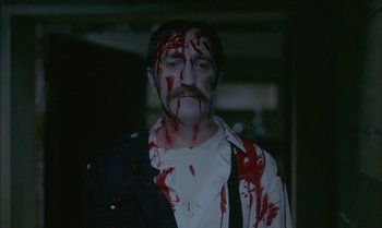 Movie still from “The Discreet Charm of the Bourgeoisie” (1972), directed by Luis Buñuel – A man with blood all over his face and chest; Medium shot, High angle