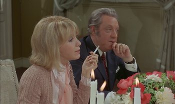 Movie still from “The Discreet Charm of the Bourgeoisie” (1972), directed by Luis Buñuel – A man and a woman sitting in front of a table; Medium shot, Over the shoulder angle