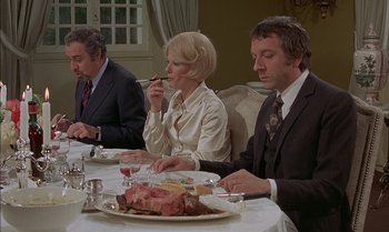 Movie still from “The Discreet Charm of the Bourgeoisie” (1972), directed by Luis Buñuel – A group of people sitting at a dinner table; Medium shot, High angle