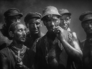 Movie still from “The Docks of New York” (1928), directed by Josef von Sternberg – Black and white photograph of a group of men smoking cigarettes; Medium shot, High angle