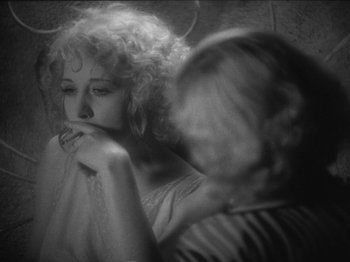 Movie still from “The Docks of New York” (1928), directed by Josef von Sternberg – A woman with curly blonde hair is looking at another woman with her hand on her chin; Close Up shot, Over the shoulder angle