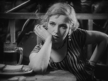 Movie still from “The Docks of New York” (1928), directed by Josef von Sternberg – A black and white photo of a woman sitting at a table; Close Up shot, High angle