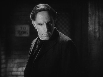 Movie still from “The Docks of New York” (1928), directed by Josef von Sternberg – A man in a suit and tie standing in front of a brick wall; Close Up shot, Low angle