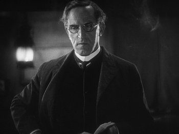 Movie still from “The Docks of New York” (1928), directed by Josef von Sternberg – A man in a suit and glasses looking at the camera; Close Up shot, Low angle