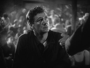 Movie still from “The Docks of New York” (1928), directed by Josef von Sternberg – An older man in a black shirt is looking at a crowd; Close Up shot, Over the shoulder angle