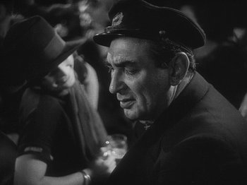 Movie still from “The Docks of New York” (1928), directed by Josef von Sternberg – An older man wearing a hat is holding a glass of wine; Close Up shot, Over the shoulder angle