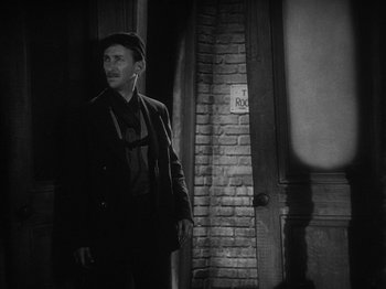 Movie still from “The Docks of New York” (1928), directed by Josef von Sternberg – A black and white photo of a man standing in front of a brick wall; Medium shot, Low angle