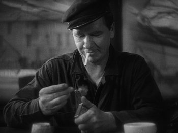 Movie still from “The Docks of New York” (1928), directed by Josef von Sternberg – A black and white photo of a man smoking a pipe; Close Up shot, High angle