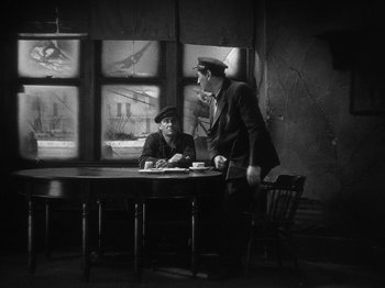 Movie still from “The Docks of New York” (1928), directed by Josef von Sternberg – Two men sitting at a table in front of a window; Wide shot, High angle