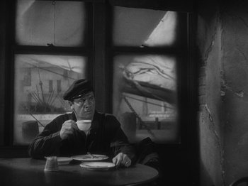 Movie still from “The Docks of New York” (1928), directed by Josef von Sternberg – A man sitting at a table drinking a cup of coffee; Medium shot, High angle