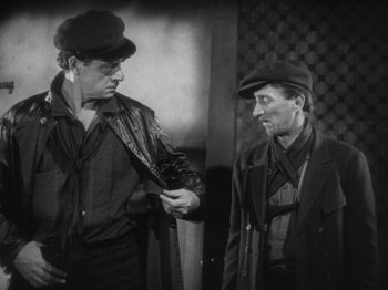 Movie still from “The Docks of New York” (1928), directed by Josef von Sternberg – Two men are standing next to each other and one is holding a hat; Medium shot, Over the shoulder angle