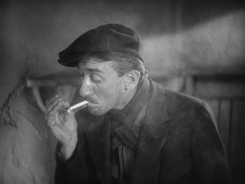 Movie still from “The Docks of New York” (1928), directed by Josef von Sternberg – An older man smoking a cigarette in a black and white photo; Close Up shot, High angle