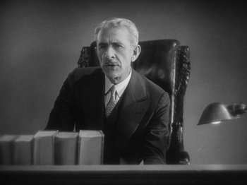 Movie still from “The Docks of New York” (1928), directed by Josef von Sternberg – An older man sitting at a desk in a suit; Medium shot, Low angle