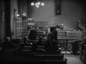 Movie still from “The Docks of New York” (1928), directed by Josef von Sternberg – A group of people sitting in front of a court room; Extreme Wide shot, High angle