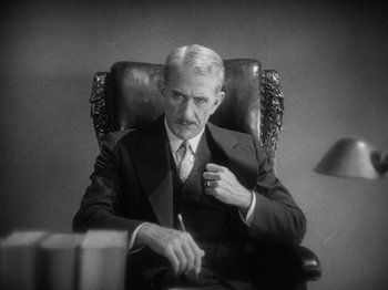 Movie still from “The Docks of New York” (1928), directed by Josef von Sternberg – An older man sitting in a chair with a pen in his hand; Close Up shot, High angle