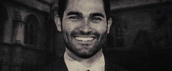 Movie still from “The Domestics” (2018), directed by Mike P. Nelson – Black and white photograph of a man smiling for the camera; Close Up shot, Overhead angle