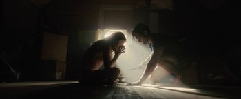 Movie still from “The Domestics” (2018), directed by Mike P. Nelson – A man and a woman sitting on the floor in a room; Wide shot, Low angle