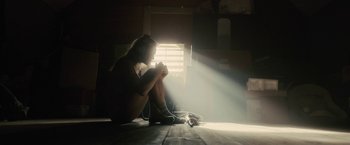 Movie still from “The Domestics” (2018), directed by Mike P. Nelson – A woman sitting on the floor in front of a window; Wide shot, Low angle