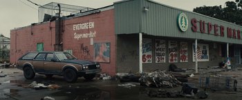 Movie still from “The Domestics” (2018), directed by Mike P. Nelson – A truck parked in front of a store; Extreme Wide shot, Low angle