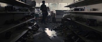 Movie still from “The Domestics” (2018), directed by Mike P. Nelson – A man standing in a room filled with papers; Wide shot, High angle