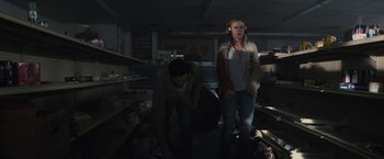 Movie still from “The Domestics” (2018), directed by Mike P. Nelson – A man and a woman are standing in a dark room; Medium shot, Low angle