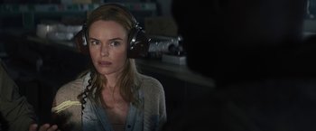 Movie still from “The Domestics” (2018), directed by Mike P. Nelson – A woman wearing headphones and looking at the camera; Close Up shot, Over the shoulder angle