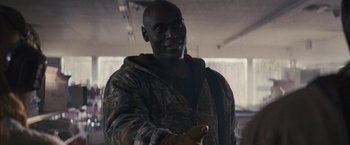 Movie still from “The Domestics” (2018), directed by Mike P. Nelson – A man in a camouflage jacket is holding his hands out; Medium shot, Over the shoulder angle