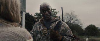 Movie still from “The Domestics” (2018), directed by Mike P. Nelson – A man in a camouflage jacket and gloves; Close Up shot, Over the shoulder angle