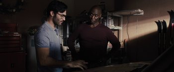 Movie still from “The Domestics” (2018), directed by Mike P. Nelson – Two men are looking at a computer screen; Medium shot, Over the shoulder angle